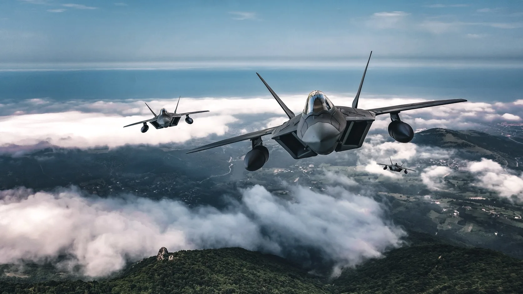 Three U.S. Air Force F-22 Raptors flying in formation above a cloud layer